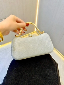 Detail of silver glitter evening clutch bag with gold metal handle and rhinestone clasp