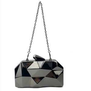 Detail of black geometric acrylic evening clutch featuring mirror finish and metal chain