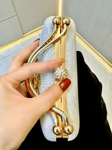 Detail of silver sequined evening clutch with gold metal handle and crystal lock