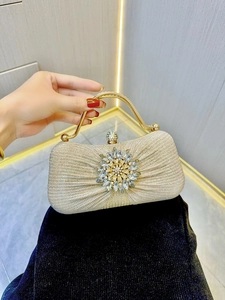 Detail of champagne gold evening clutch with sunflower crystal ornament and diamond clasp