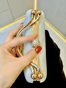 Detail of silver sequin evening clutch bag with golden handle and rhinestone lock