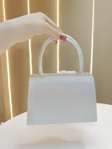 Detailed view of silver glitter evening bag with rhinestone edge and structured handle