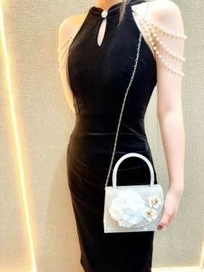 Detail of elegant white saddle evening bag with large 3D flower and shimmering rhinestones