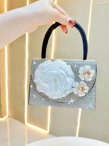Detailed view of silver rhinestone evening bag with handcrafted large white satin rose