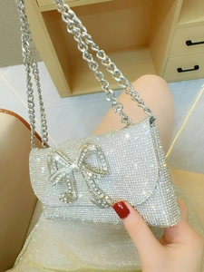 Elegant silver evening clutch bag with sparkling diamond bow and metallic chain strap