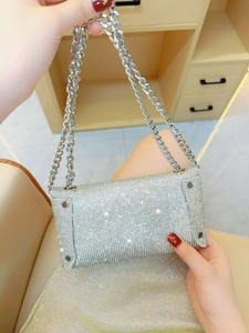 Detail shot of shimmering silver rhinestone clutch with luxury metal chain strap