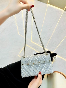 Macro view of geometric crystal and pearl embroidery on silver evening bag clutch