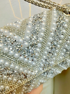 Close-up of evening bag with white pearls, crystals and light gold metal chain detail