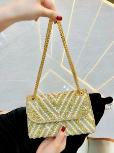 Detailed macro view of an evening clutch with white pearls, crystals, and gold chain