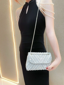 Close-up of pearl and rhinestone clutch bag with metal chain strap held by a model