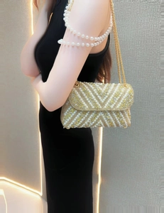 Detail of elegant gold evening bag with white pearls and sequins in V-shape pattern