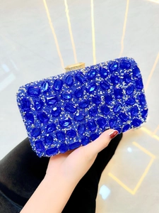 Détail d'une pochette de soirée bleu roi avec strass scintillants tenue à la main