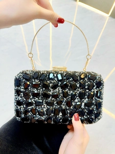 Détail d'une pochette de soirée noire luxueuse avec strass et poignée anneau dorée