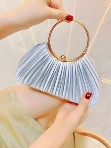 Détail d'une pochette élégante en satin plissé avec une grande poignée ronde dorée de soirée