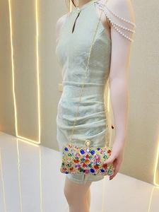 Detail of evening clutch featuring colorful floral gemstones and a large pearl clasp