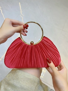Détail de la pochette de soirée en satin plissé rouge avec poignée ronde dorée chic