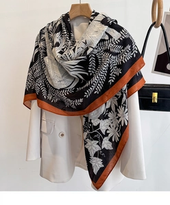 Detailed view of large printed scarf draped over a blazer showing daisy and vine patterns