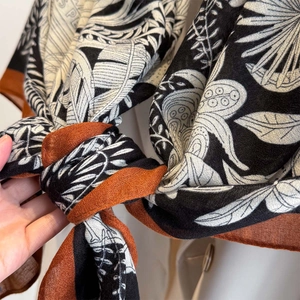 Close-up of bohemian leaf print scarf with contrast rust red borders and soft texture