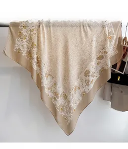 Detailed view of large square champagne scarf with daisy prints and soft silk-like texture