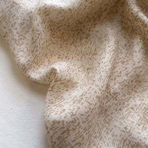 Close-up of lightweight linen texture scarf featuring brown abstract geometric patterns