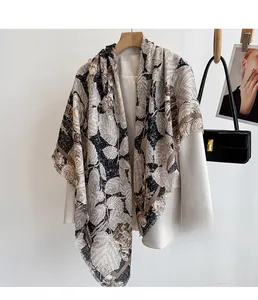 Detail of vintage leaf print silk scarf styled over a beige blazer for sun protection
