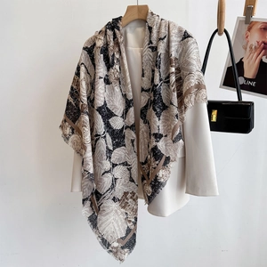 Close-up of vintage print shawl scarf with fine tassel fringe on white blazer