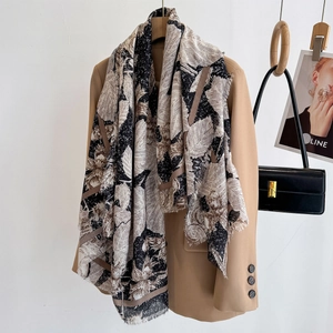 Abstract leaf print pashmina shawl with tassel fringe draped over a beige blazer