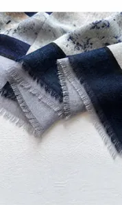 Nahaufnahme eines Schals mit geometrischem Muster, Fransen und weicher Textur