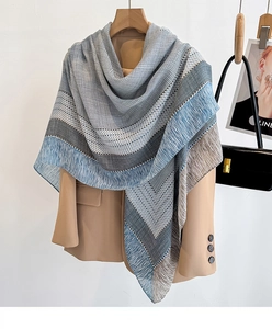 Detail of blue geometric plaid scarf with tassel edges on a camel blazer coat