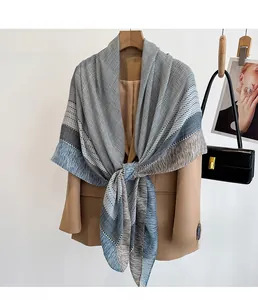 Detail of blue and grey houndstooth scarf with fringe styled on a camel blazer coat
