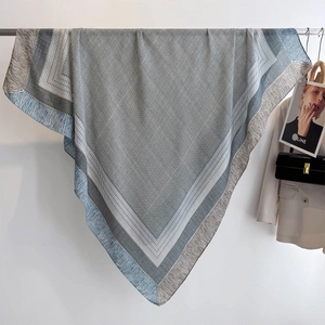 Blue-gray striped square scarf with geometric dots draped next to a beige blazer