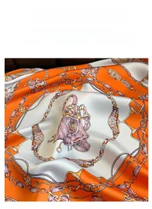 Close-up of luxury satin silk scarf with orange chain and vintage handbag patterns