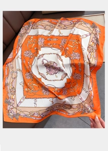 Detail of elegant orange chain pattern silk scarf with satin finish on leather background