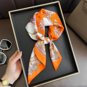 Fashionable orange and white chain print silk scarf styled in a luxury gift tray