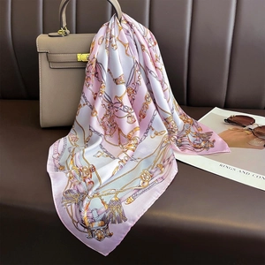 Pink and purple gradient silk scarf with gold chain print draped over a luxury handbag
