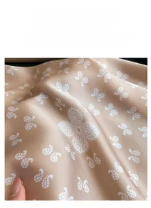 Vue détaillée du tissu satiné champagne doré avec motifs floraux paisley blancs