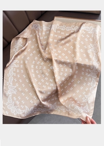 Détail d'un foulard en soie champagne avec motif paisley et texture satinée brillante