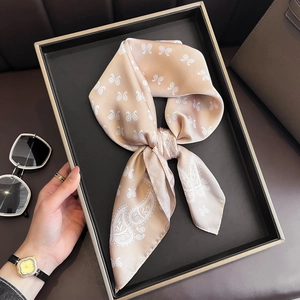 Détail d'un foulard en soie champagne à motifs paisley avec montre et lunettes