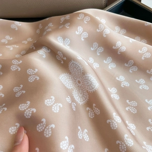Gros plan d'un foulard en soie champagne avec imprimé paisley montrant le drapé et la texture