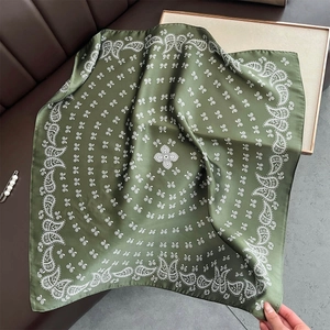 Gros plan du foulard carré en satin vert foncé avec motif cachemire et texture soyeuse
