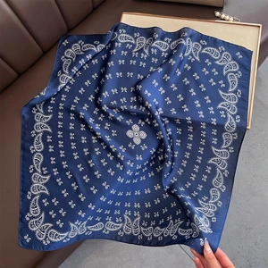Détail du foulard en soie bleu marine avec motif paisley blanc sur surface en cuir