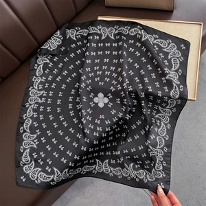 Détail d'un foulard en soie noire avec motif cachemire blanc et imprimés géométriques