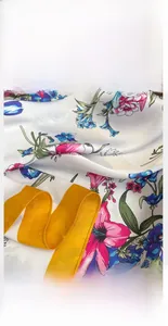 Detailed close-up of floral silk scarf showing fine stitching and yellow rolled edges