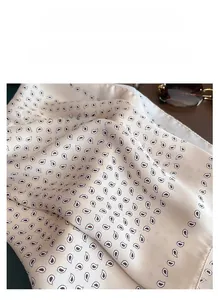Dettaglio di sciarpa in raso champagne con stampe paisley ed eleganti drappeggi