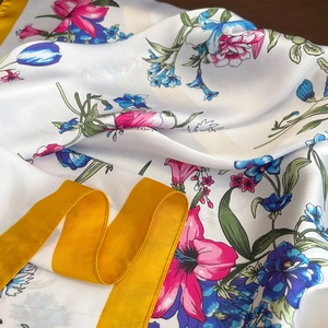 Detailed close-up of floral print silk scarf with vivid colors and yellow border