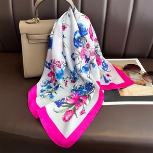 Floral faux silk square scarf draped on a handbag with realistic blossoms and pink border