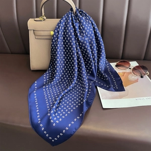 Sciarpa di seta blu navy con motivo paisley annodata a una borsa per un look professionale