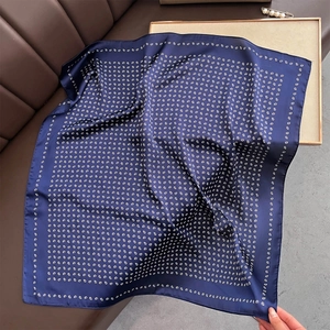 Dettaglio di un foulard in raso blu scuro con stampa paisley su superficie di pelle