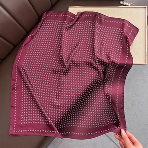Dettaglio di sciarpa in seta bordeaux con stampa paisley su divano in pelle e vassoio