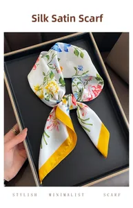 Detail of satin silk-like square scarf with floral print and bright yellow edges in a tray
